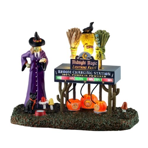 Whimsical Halloween display with a purple-clad witch statue beside a sign says 'Broom Charging Station' and glowing pumpkins under a rustic stand.